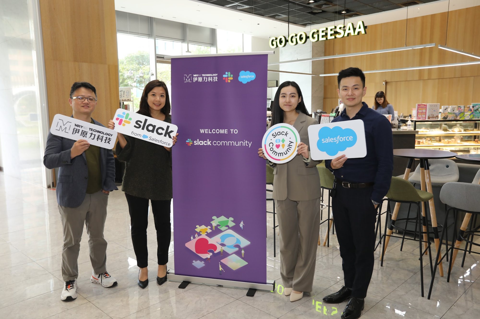 伊原力科技、Slack 與 Salesforce 團隊手持品牌手板,於 Slack Community 背板前合影